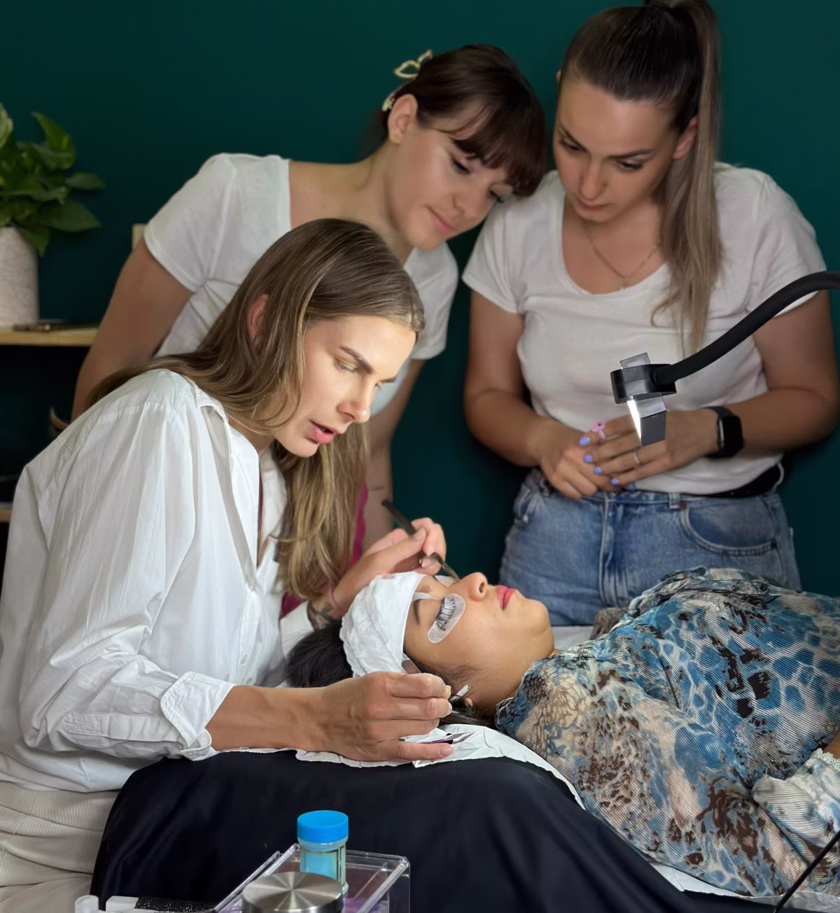 Viktorija applying eyelash extensions in front of students